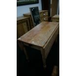 A pine scrub top drop-flap farmhouse kitchen table with cutlery drawer to end,