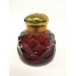 A heavy ruby cut glass ink bottle with brass lid.