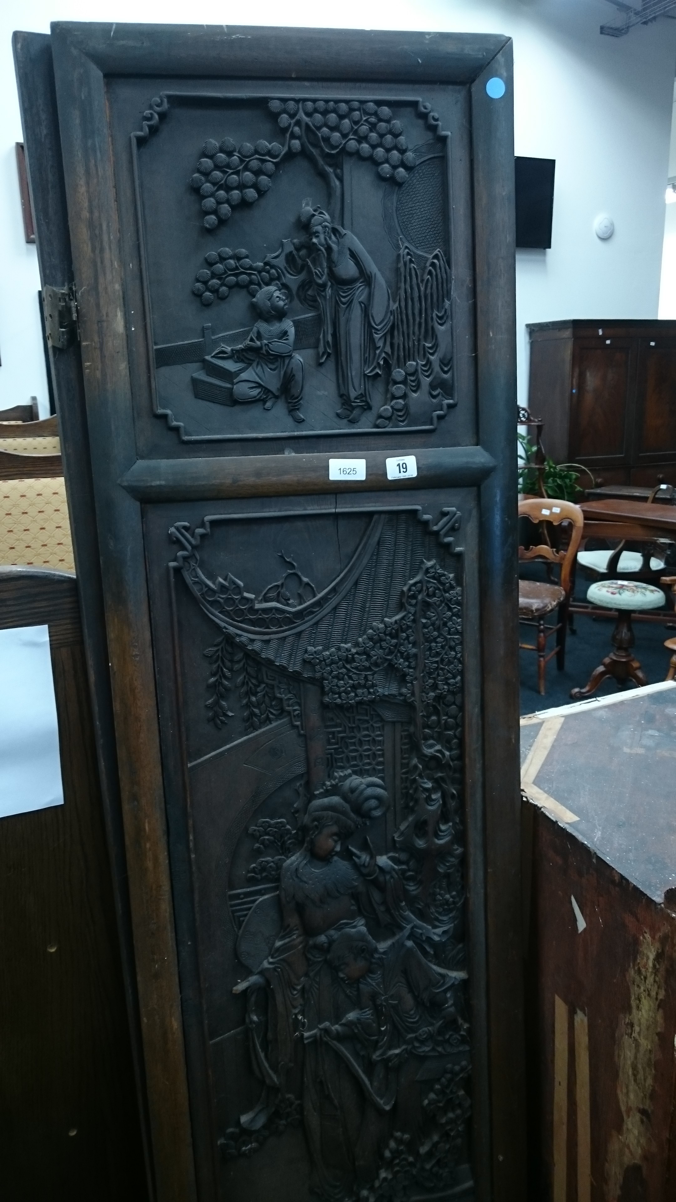 A heavily carved Chinese hardwood four fold screen with panels depicting figures and foliage.