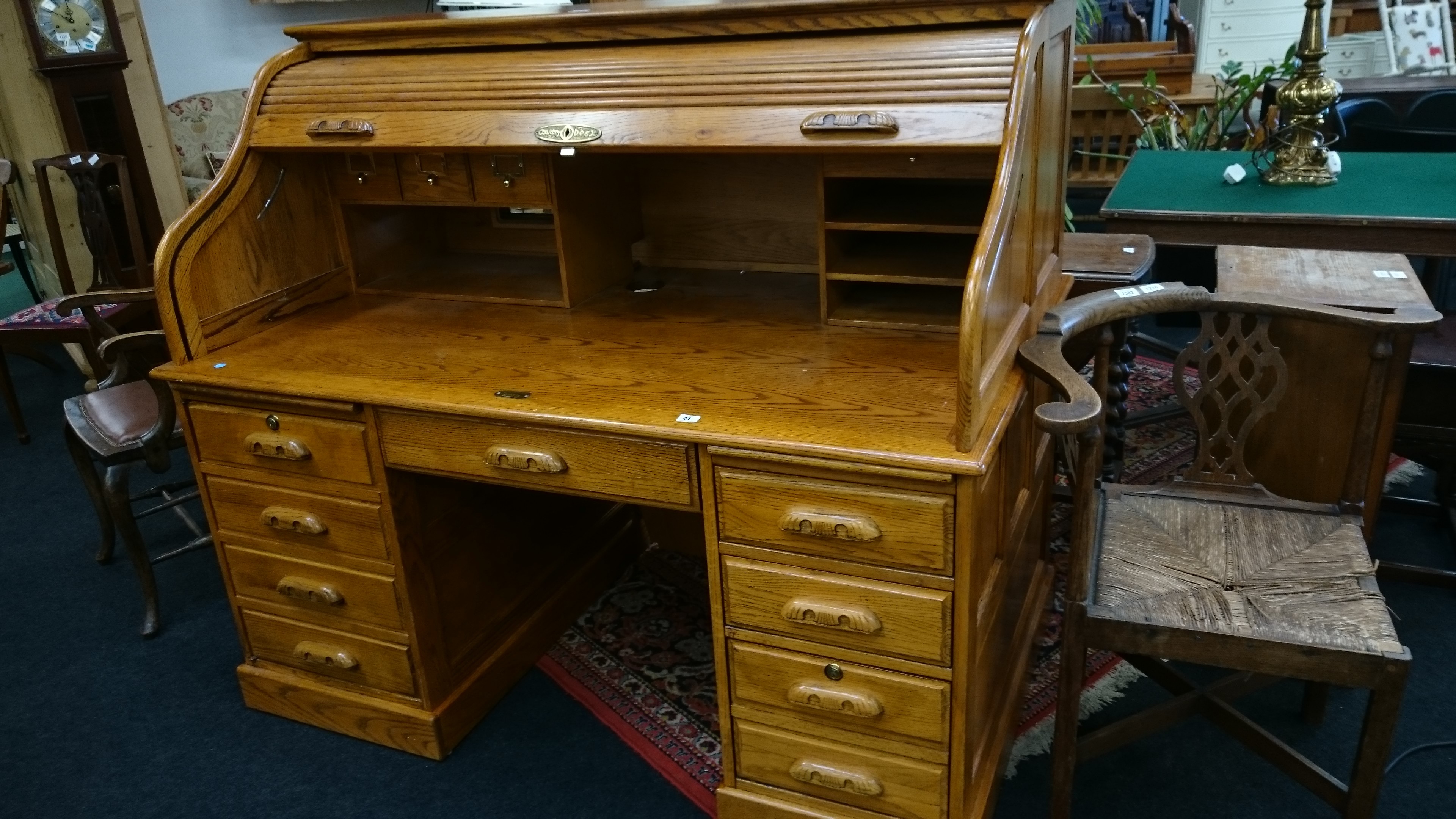 A large oak modern reproduction roll-top desk with eight drawers below and centre drop-down panel
