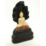 An unusual Eastern ivory and hardwood ornament modelled as a cross legged Buddha on snake throne