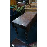 A mahogany Victorian Pembroke table resting on turned supports.