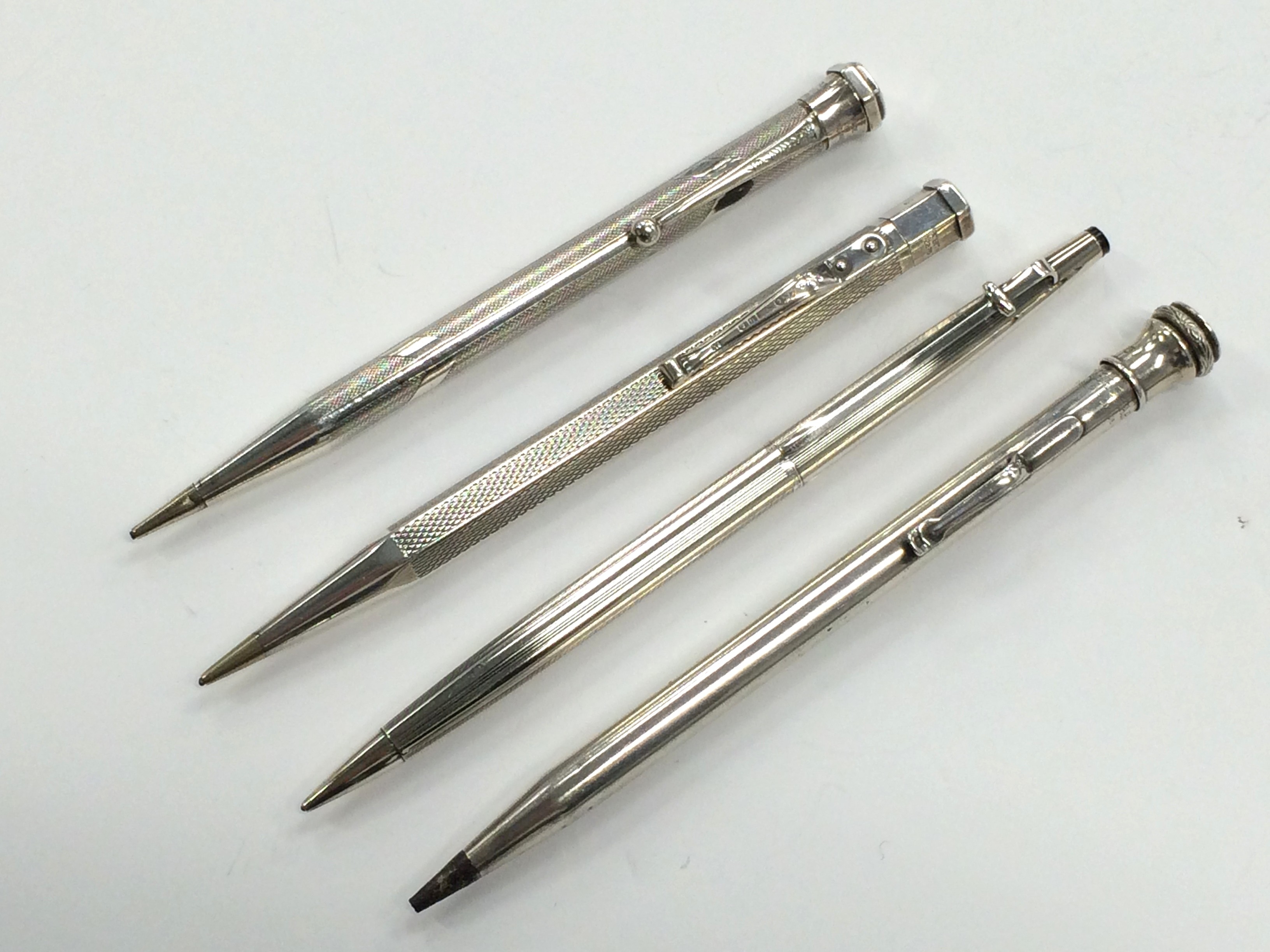 A silver Caran D'ache propelling pencil together with three other silver cased propelling pencils.