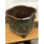 A cast iron oviform planter decorated with lions masks resting on three paw feet (one missing).