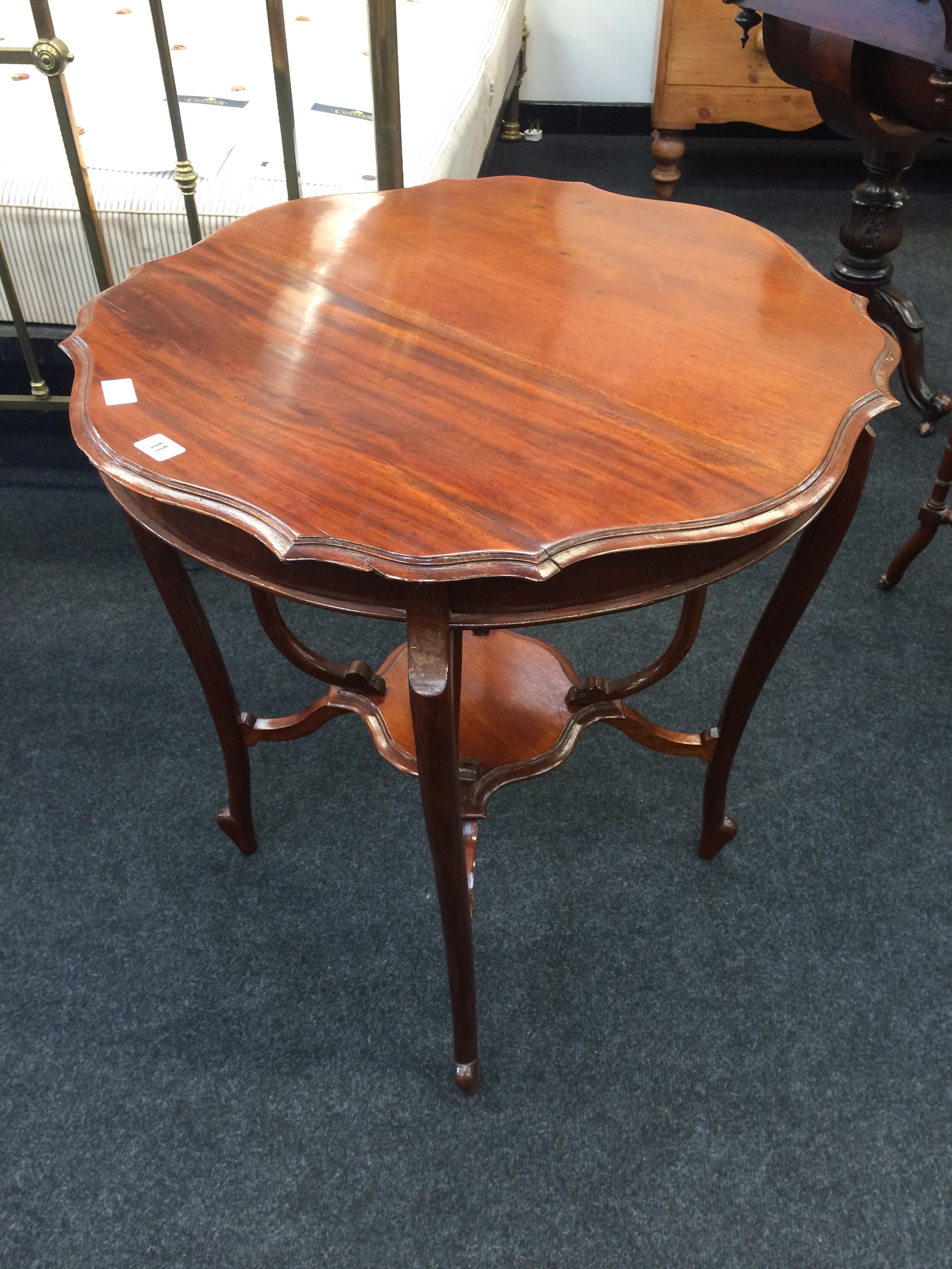 A Victorian mahogany shaped top occasional table resting on carved outswept legs and jardiniere