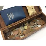 A wooden box containing various coins.