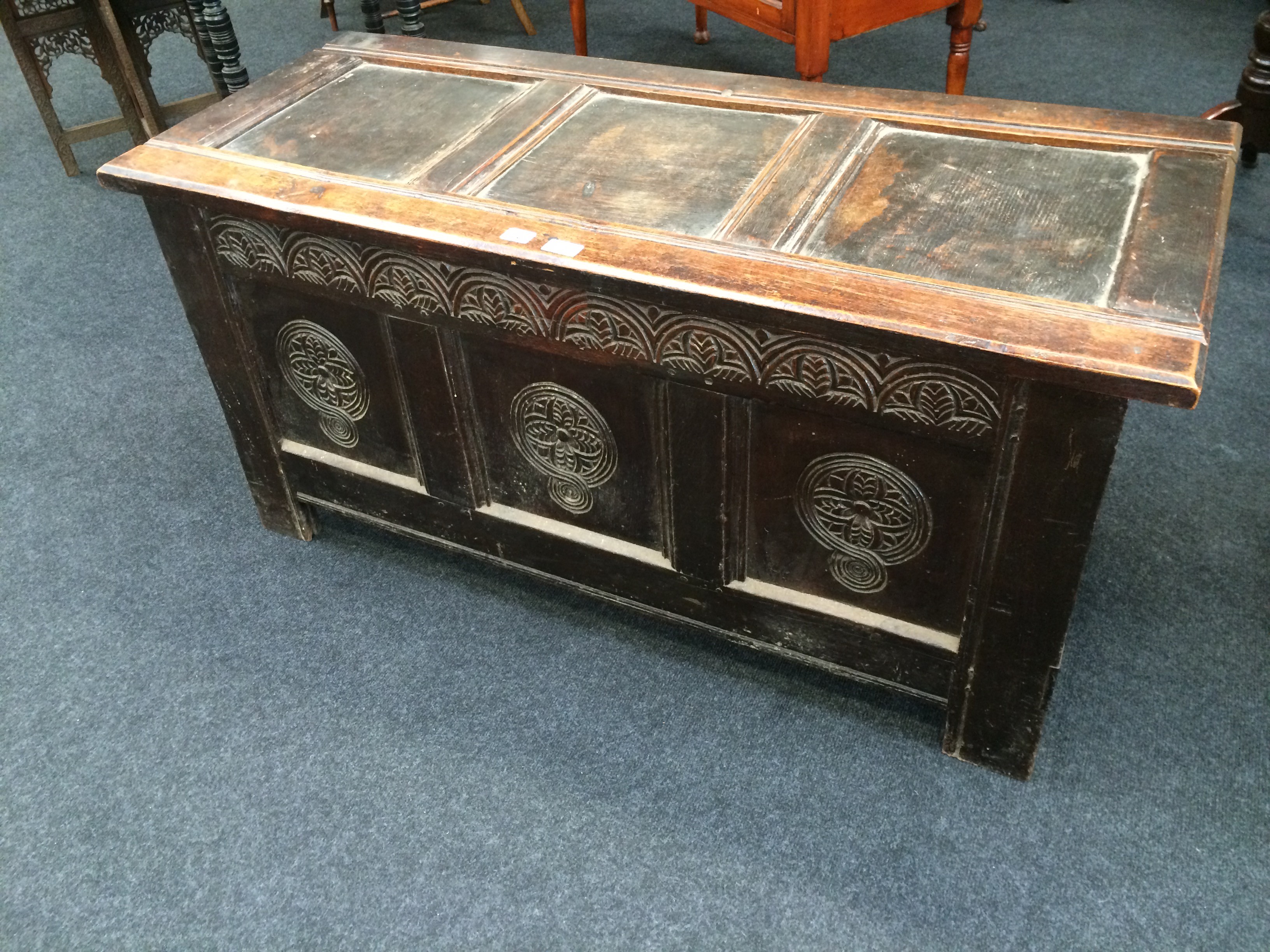 An antique oak carved front three panelled coffer.