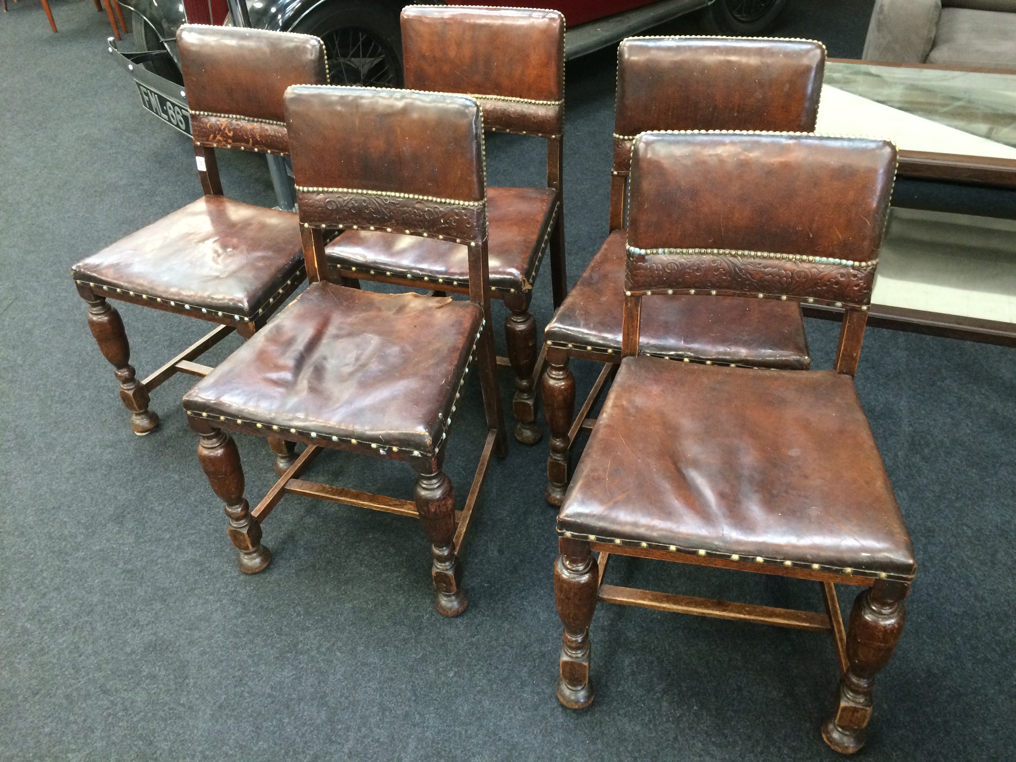 A set of five oak and leather back Cromwellian dining chairs.