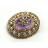 A 9 carat gold oval brooch set seed pearls and amethyst colour cabochon.