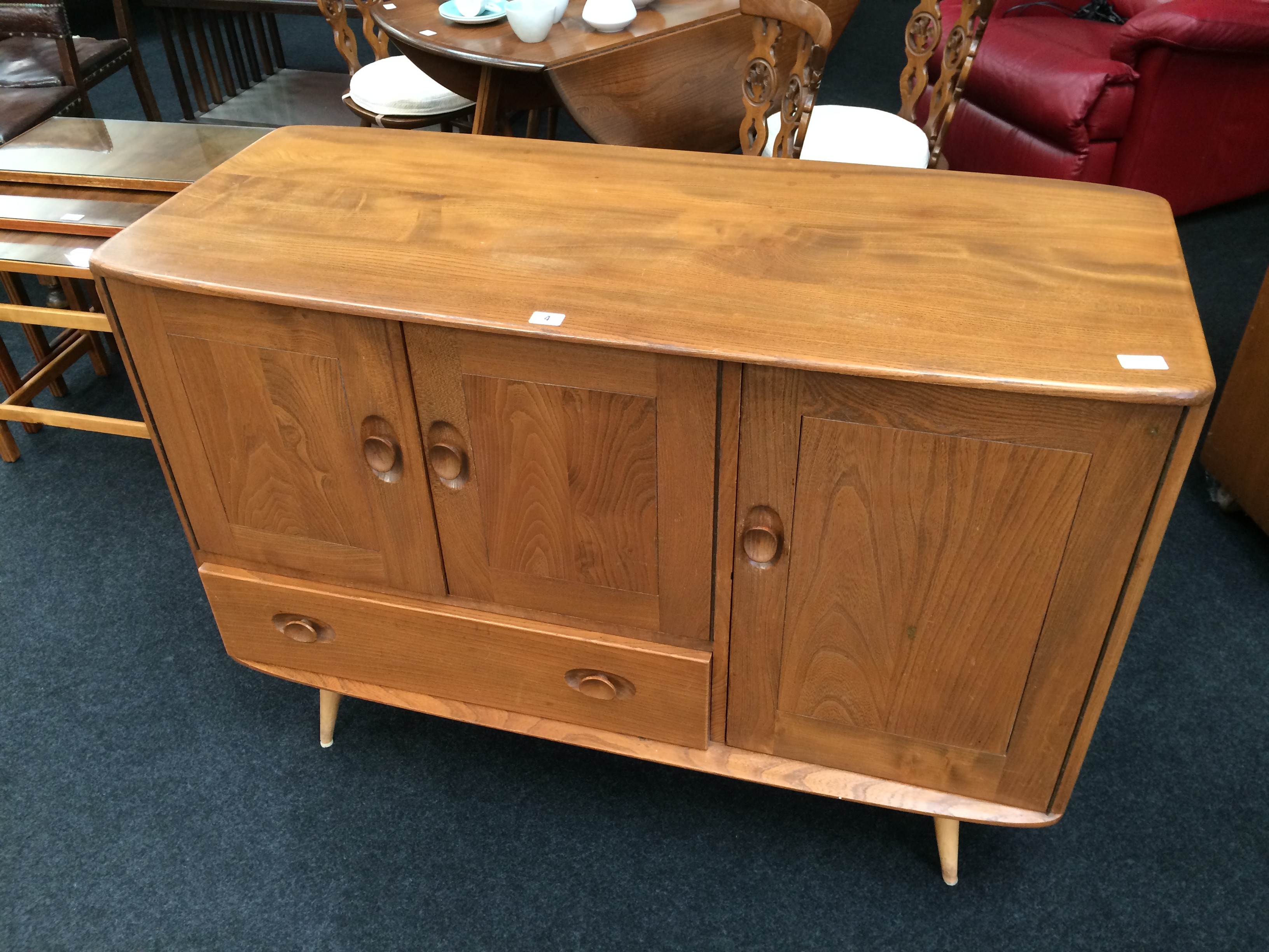 An Ercol sideboard fitted cupboard and smaller cupboard above draw resting on turned supports.