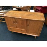 An Ercol sideboard fitted cupboard and smaller cupboard above draw resting on turned supports.