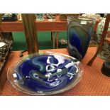 A hand blown glass bowl decorated in blue with a swirl pattern together with a similar vase.