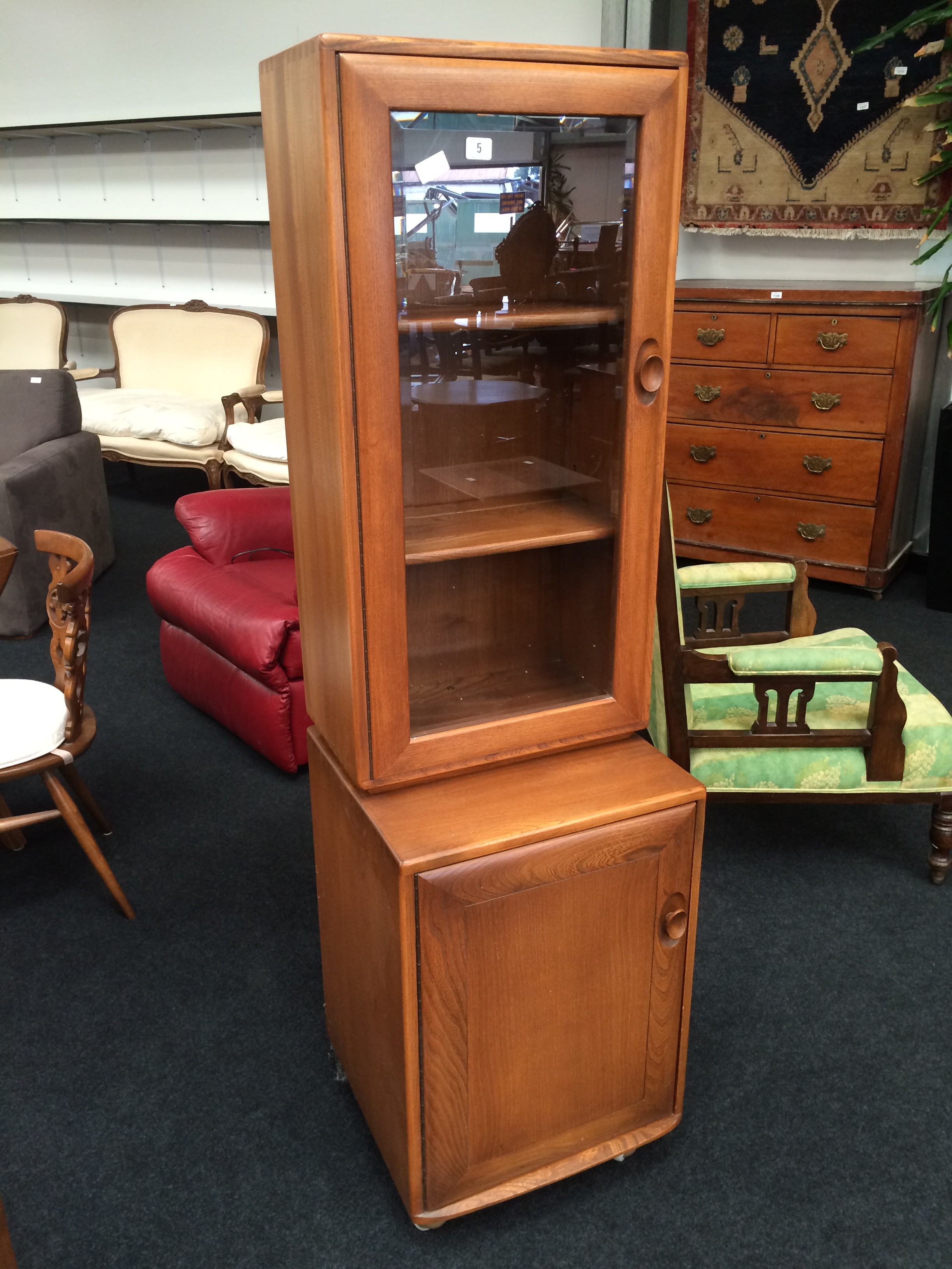 An Ercol display cabinet fitted single bevelled glass door to top and single panel door to base.