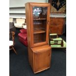 An Ercol display cabinet fitted single bevelled glass door to top and single panel door to base.