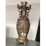 A Chinese white metal vase decorated with Dragons resting on three paw feet, stamped mark to base.