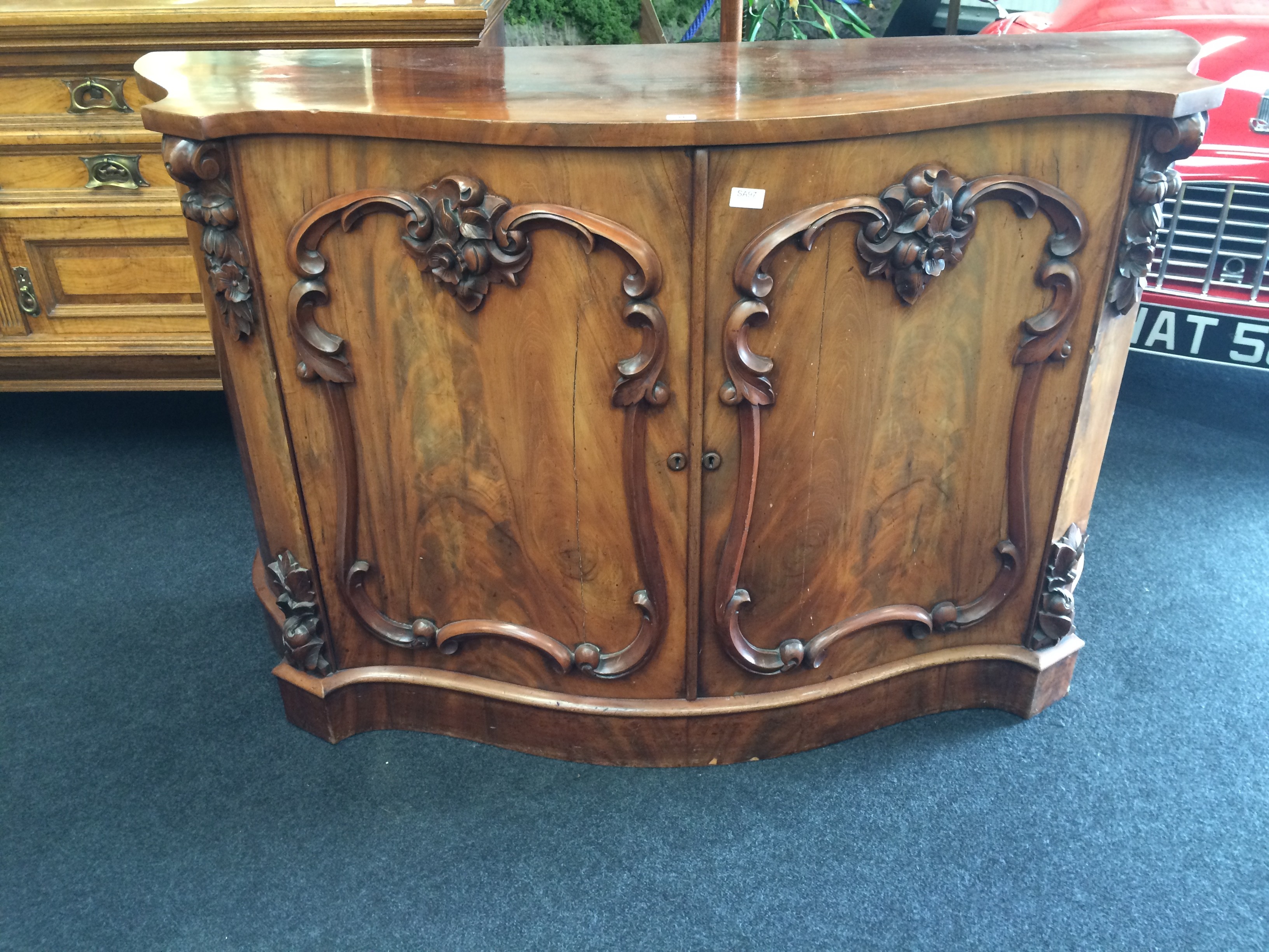 A Victorian Cuban mahogany serpentine fronted side board with fitted carved double panelled doors