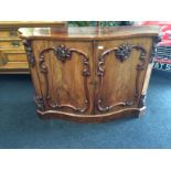 A Victorian Cuban mahogany serpentine fronted side board with fitted carved double panelled doors