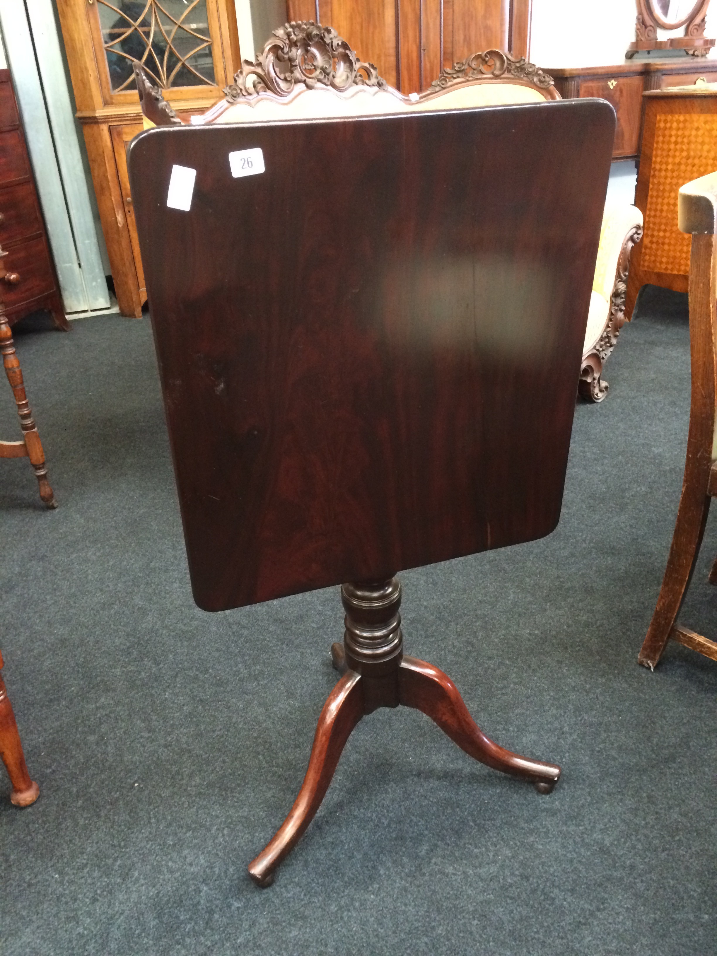 A Georgian mahogany tilt top wine table resting on a tripod base.