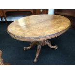 A large quarter veneer burr walnut oval snap top loo table resting on heavily carved bulbous centre