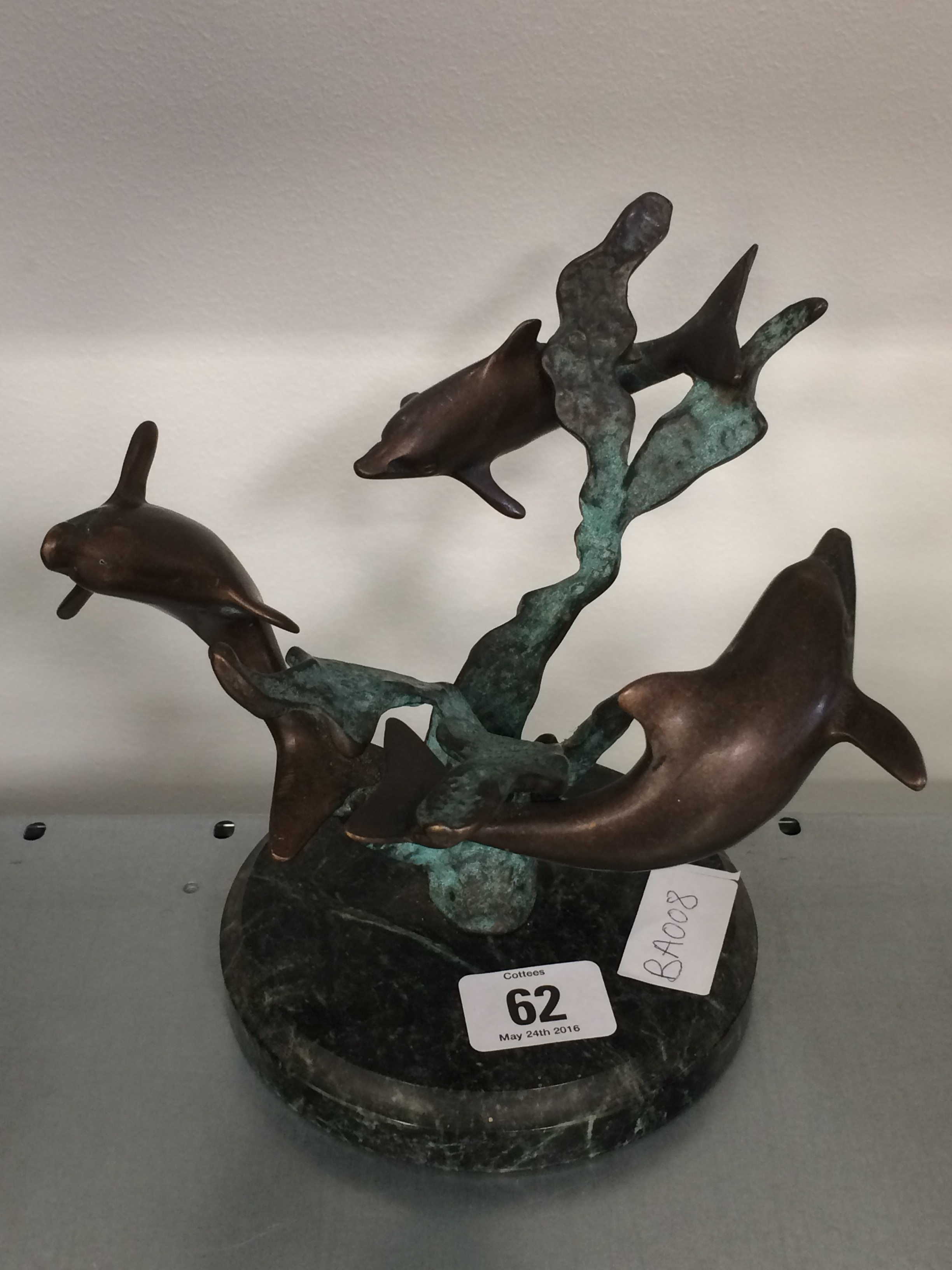 A Bronze sculpture decorated with dolphins on circular marble base.