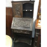 A Victorian carved oak bureau fitted with a carved cupboard to back,