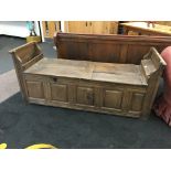 A Continental heavy oak lift-top bench seat with panelled front and enclosing side boxes.