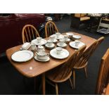 An Ercol light elm dining table and four stickback chairs.