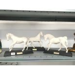 Three matt white Beswick china horses on wooden stands: Spirit of The Wind,