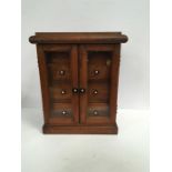 A 1920s Australian Silky oak collectors cabinet with turned ebony handles.