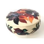 A Moorcroft Pottery circular china lidded pot with tube line floral decoration, impressed and signed