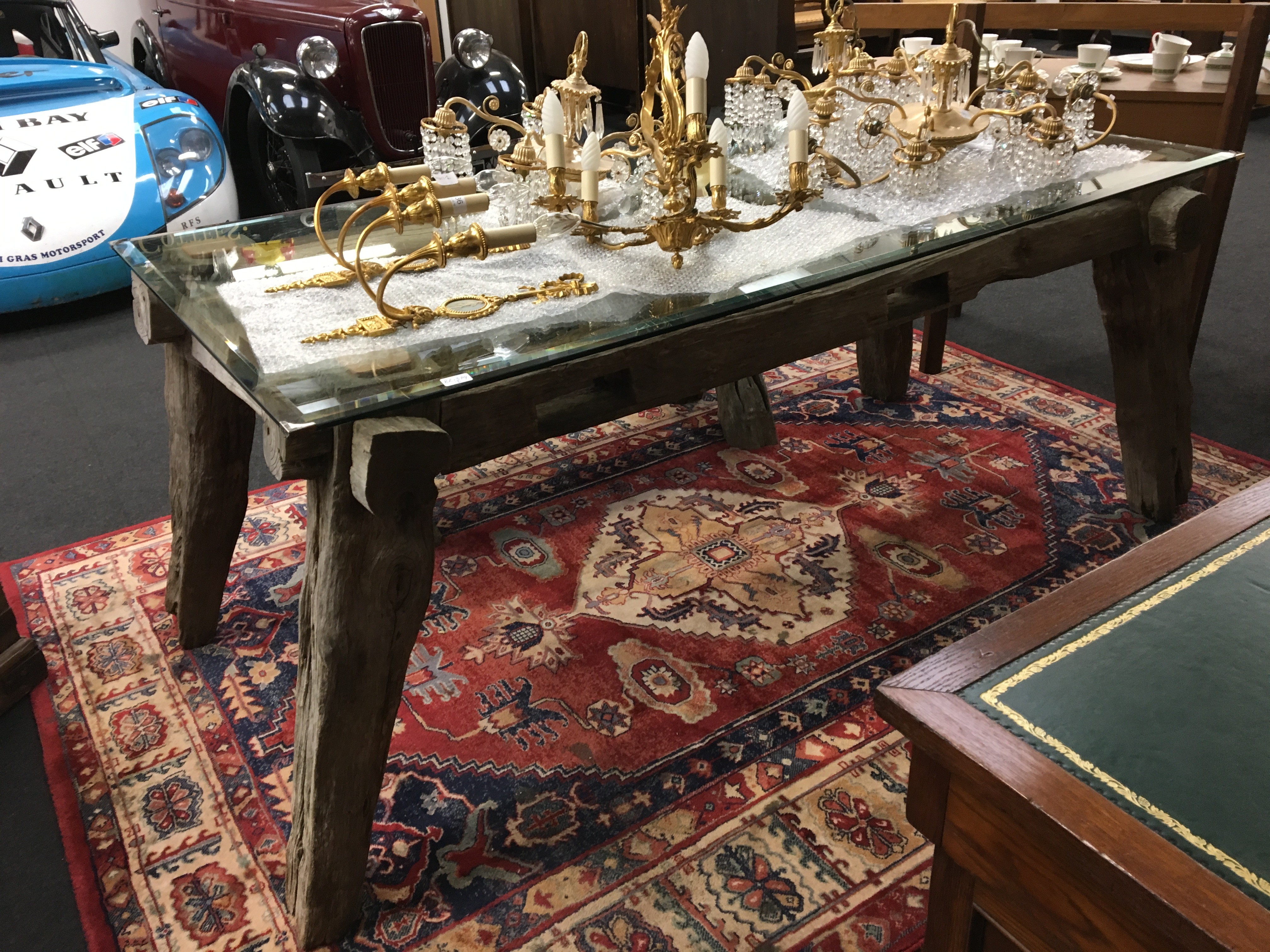 A glass topped coffee table resting on oak frame supports, made from old oak beams.