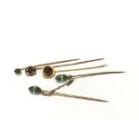 Four (including one double) gold stickpins set with various stones including Garnet, Jade etc.