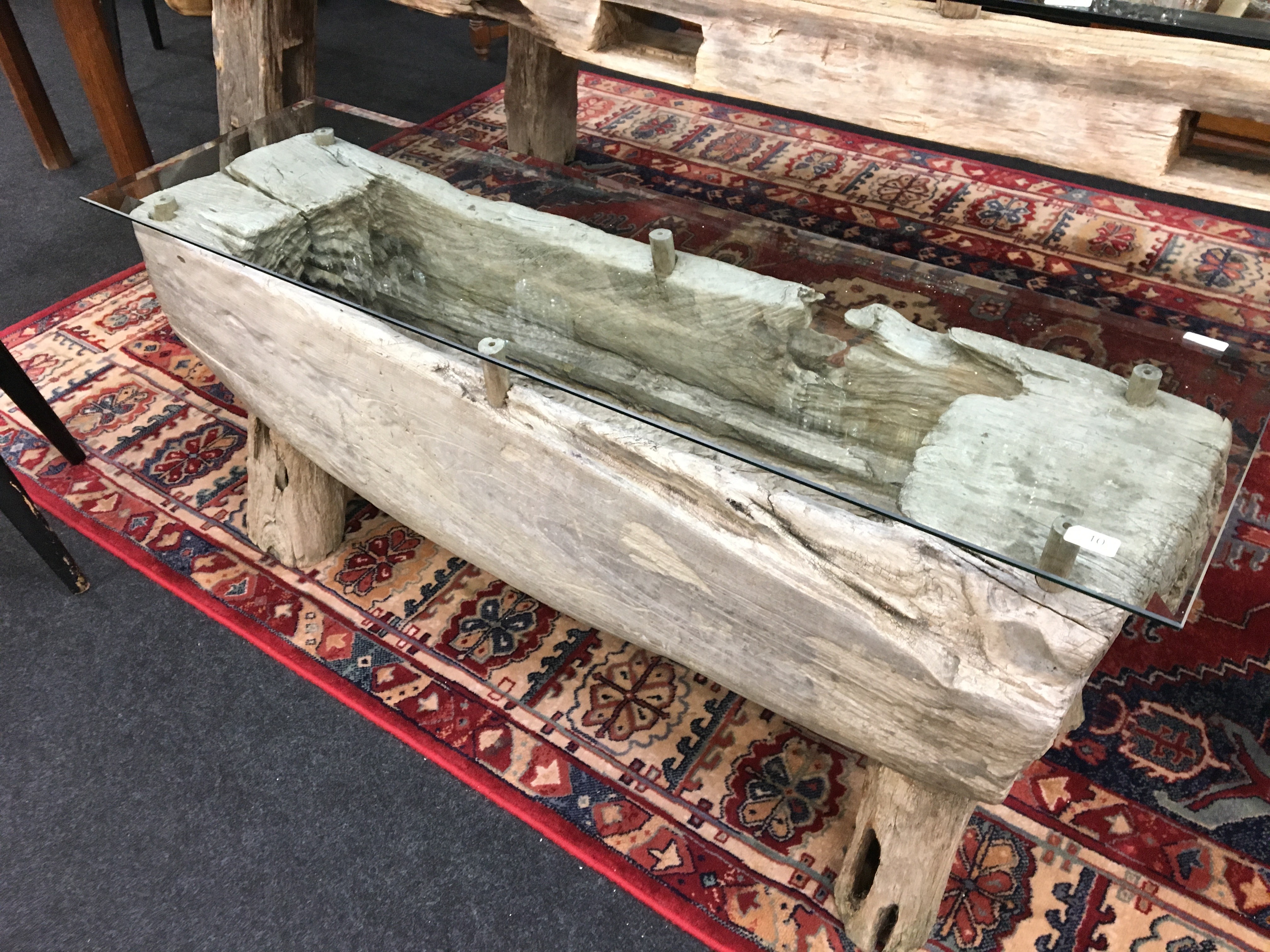 A large glass topped table resting on oak frame supports, made from old oak beams.