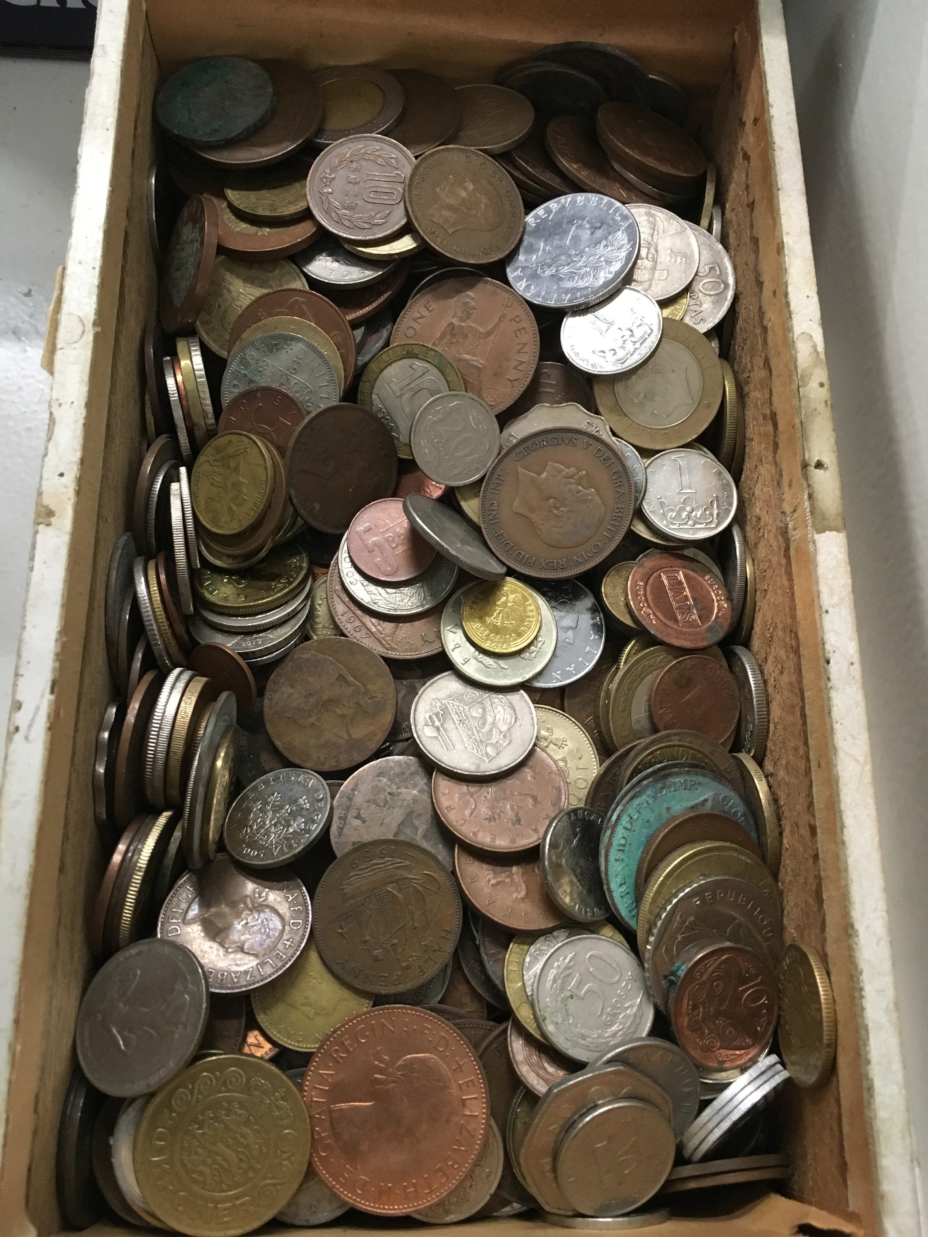 A wooden carton of mixed foreign and used coins.