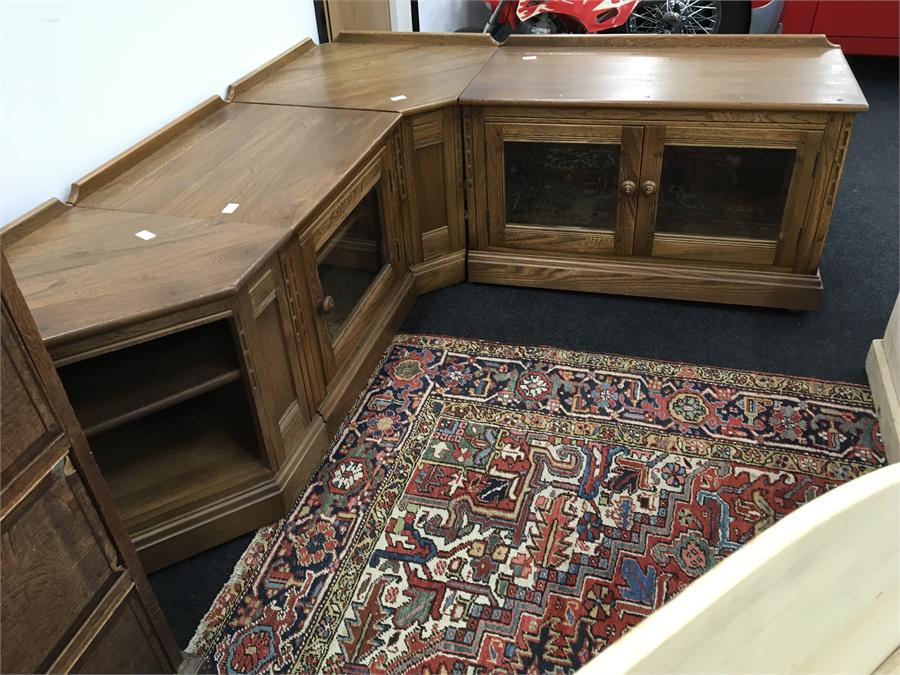 An Ercol four section TV and Hifi corner unit in light oak with glazed doors to front.