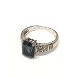 A 9ct white gold ring set with a large central blue stone and with each shoulder set with six