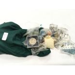 Green bag containing a collection of silver and copper coins.