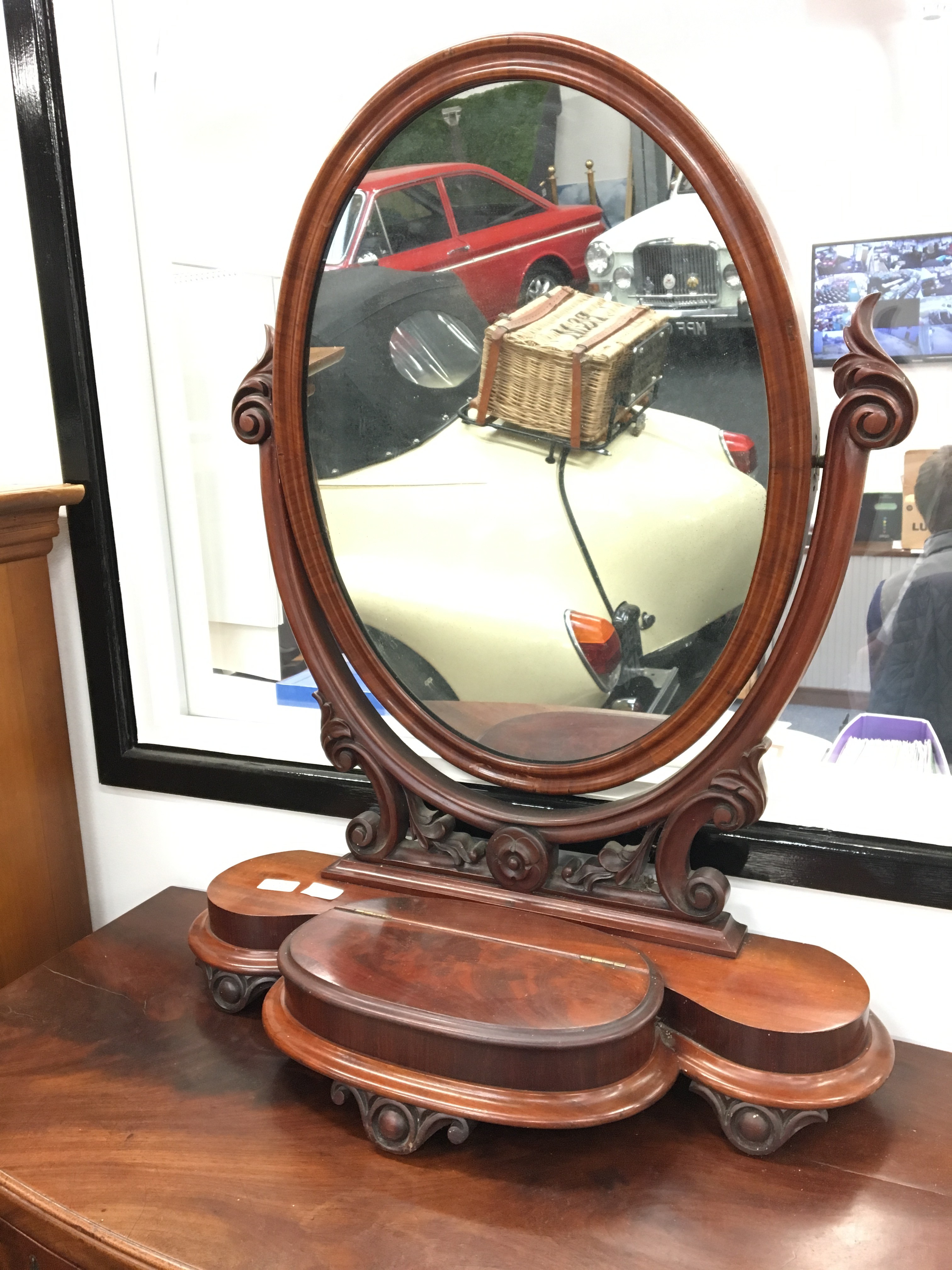 19th century mahogany oval dressing table mirror with trinket box resting on carved feet.