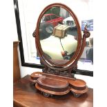 19th century mahogany oval dressing table mirror with trinket box resting on carved feet.