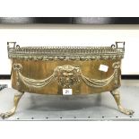 A 19th century French brass wine cooler decorated with masks and swags, resting on outswept paw