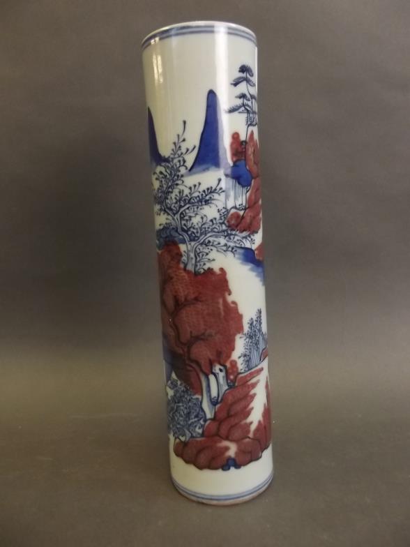 A Chinese porcelain cylindrical spill vase decorated with landscape scenes in blue and white with