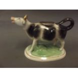 A Staffordshire pottery creamer in the form of a cow, on an oval base, 4½" high