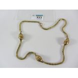 Continental gold snake chain necklace interspersed with three egg shaped links with raised