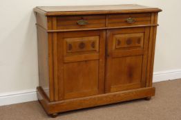 Edwardian golden oak two drawer sideboard enclosed by panelled doors with carved detail, W113cm,