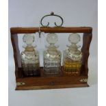 Edwardian oak three bottle tantalus with sliding drawer action,