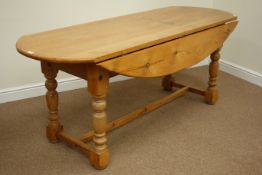 Large pine oval drop leaf dining table raised on stretcher base,