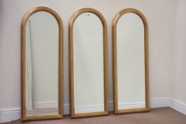 Three narrow arched top moulded gilt framed bevel edged mirrors,