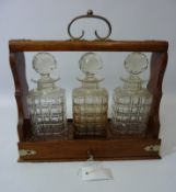 Edwardian oak three bottle tantalus with sliding drawer action,