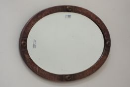 Arts and Crafts period oval bevel edged mirror, beaten copper frame,