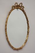 20th century oval gilt wood and gesso framed bevel edged mirror, floral decoration, bow pediment,